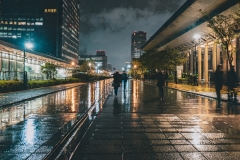 Firefly-in-a-rainy-night-the-water-on-the-street-floor-that-reflect-the-night-and-people-walking-ar